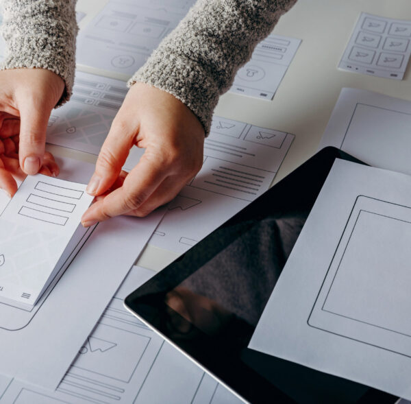 Prototyping von mobilen Anwendungen Hände platzieren Papierprototypen auf einem Tisch mit Layouts.