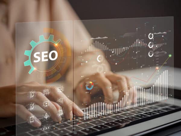 Hände tippen auf einer Tastatur, umgeben von SEO-Grafiken.