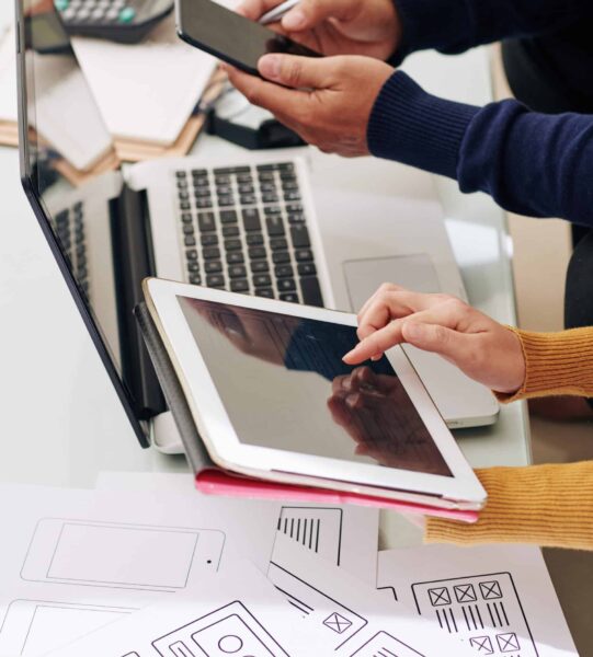 Team of ux designer and front end developer testing interface of new website on smartphone and tablet computer