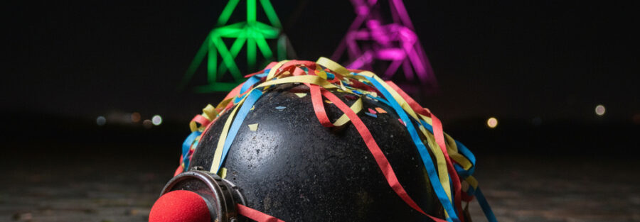 Bergmannshelm mit bunten Dekorationen vor einer Lichtinstallation.