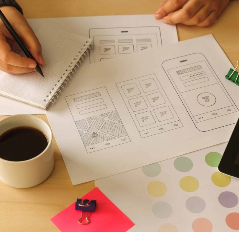 Entwurf von App-Layouts mit Notizen Notizen und Skizzen für App-Design auf einem Tisch.