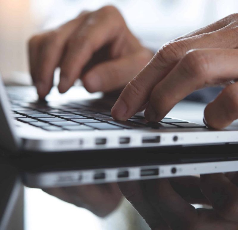 Hände tippen auf einer Laptop-Tastatur Nahaufnahme von Händen, die auf einer Laptop-Tastatur tippen.
